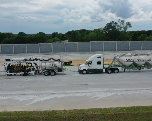 A semi truck hauling cement on the side of a road.